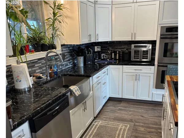 a kitchen with stainless steel appliances a stove a sink and white cabinets