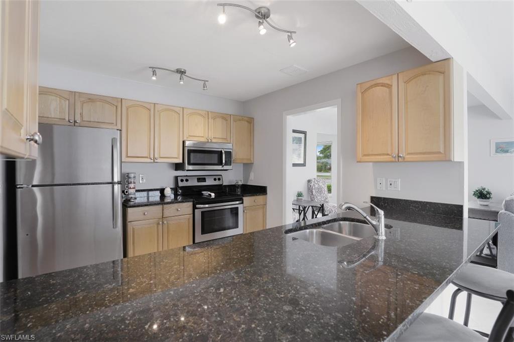 701 93rd Avenue North Naples, FL 34108 - Photo 12 of 33 a kitchen with granite countertop a refrigerator a stove a sink a counter space and cabinets