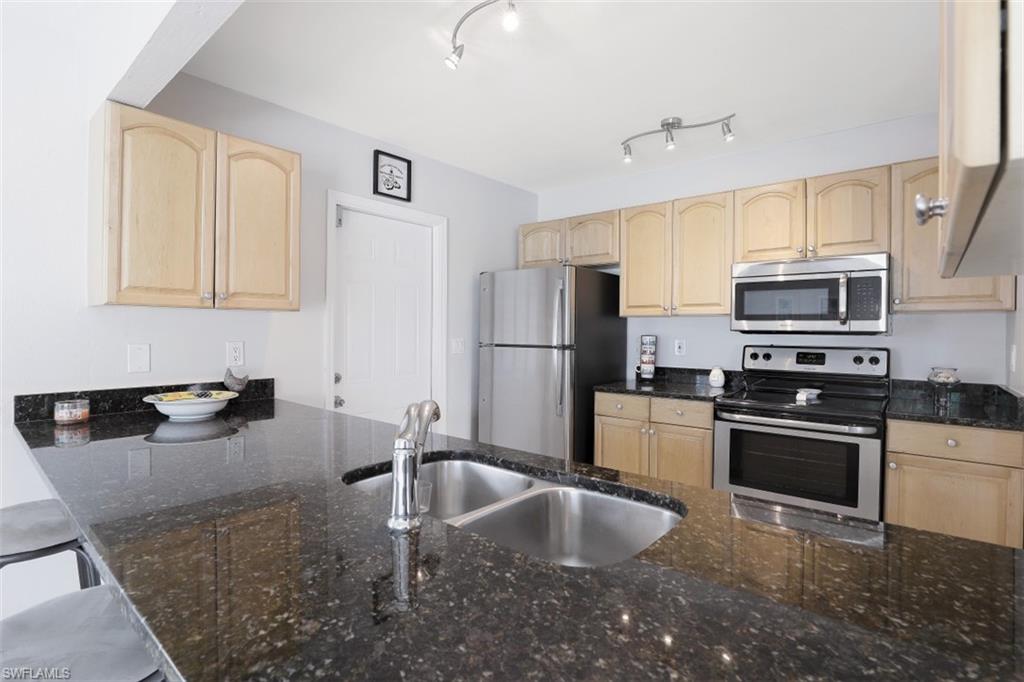 701 93rd Avenue North Naples, FL 34108 - Photo 15 of 33 a kitchen with stainless steel appliances granite countertop a sink stove and refrigerator