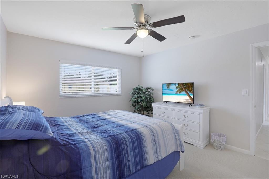701 93rd Avenue North Naples, FL 34108 - Photo 18 of 33 a bedroom with a bed a chandelier and a window