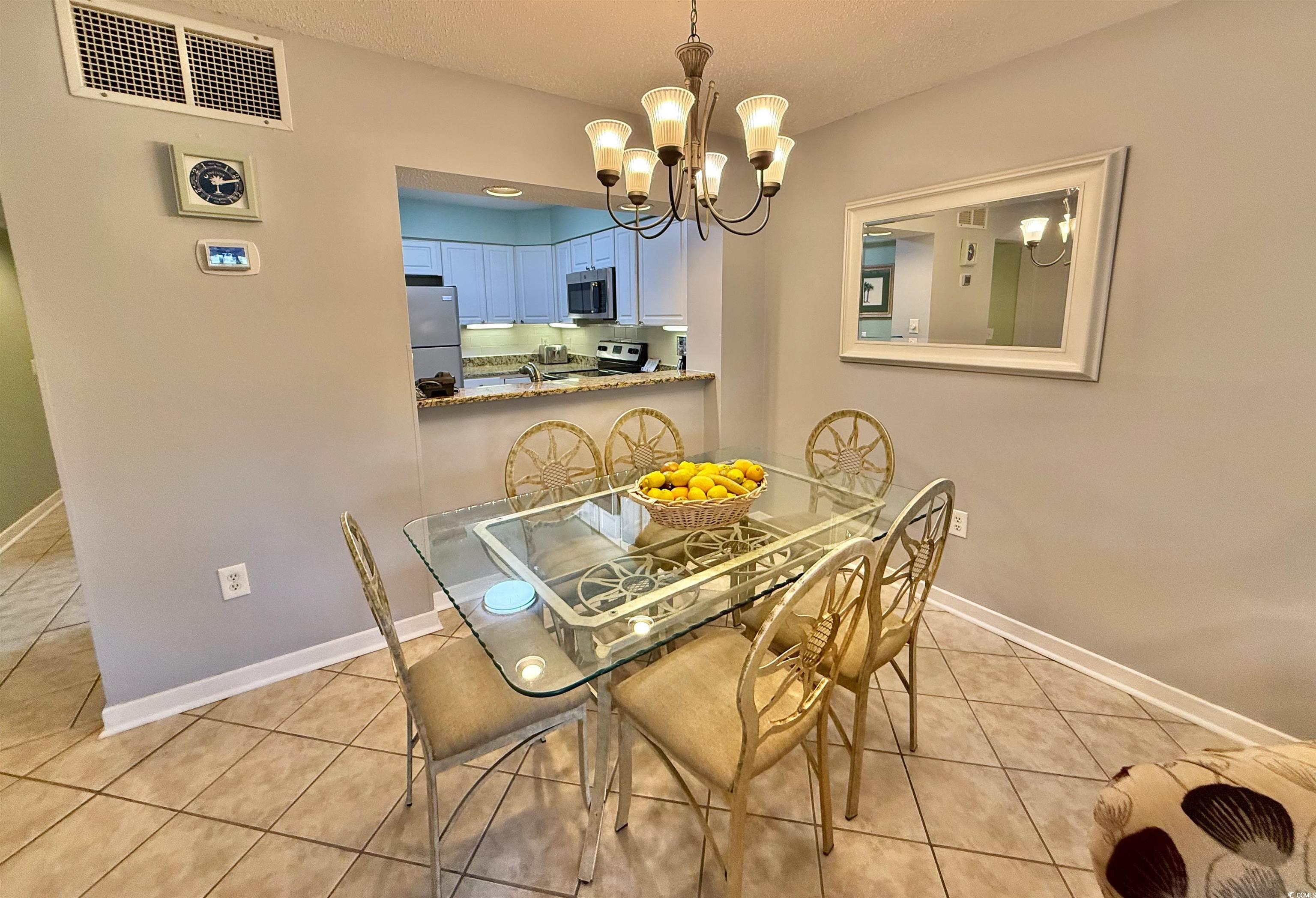 410 Melrose Place, Unit 310 Myrtle Beach, SC 29572 - Photo 14 of 39 Dining area featuring light tile patterned floors, a chandelier, and a textured ceiling
