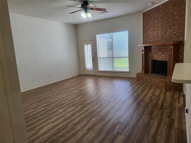 an empty room with wooden floor fireplace and windows