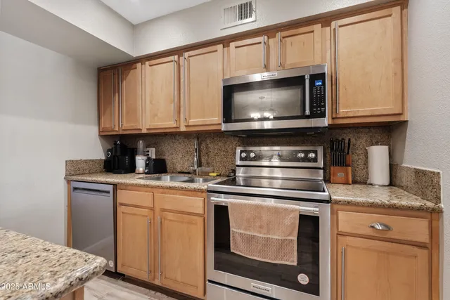 a kitchen with stainless steel appliances granite countertop a stove microwave and sink