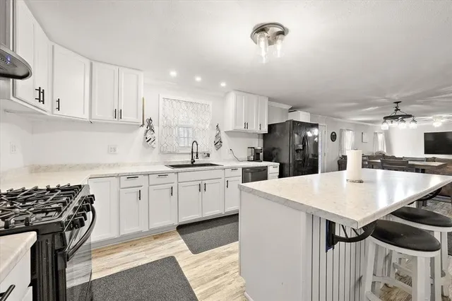 a kitchen with a sink a stove a refrigerator and white cabinets