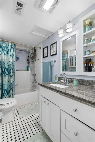 a bathroom with a granite countertop sink a toilet a mirror a bathtub and shower