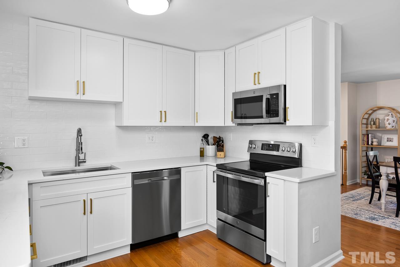 7724 Cart Track Trail Raleigh, NC 27615 - Photo 8 of 28 a kitchen with cabinets stainless steel appliances and wooden floor