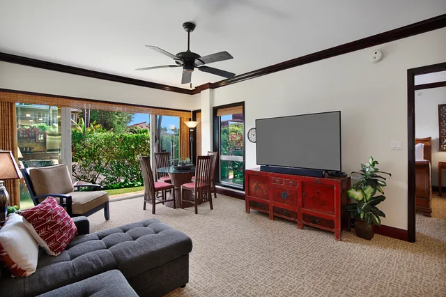 a living room with furniture a ceiling fan and a large window