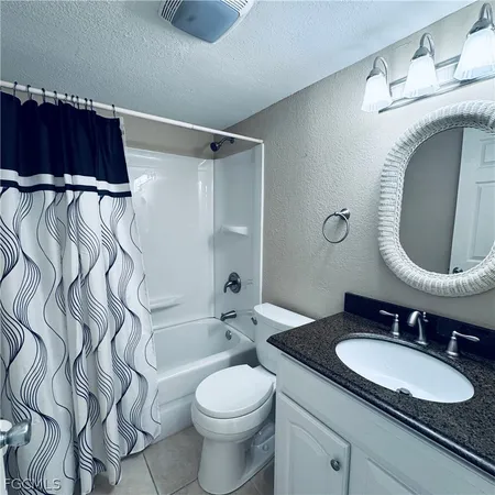 a bathroom with a granite countertop sink a mirror and shower
