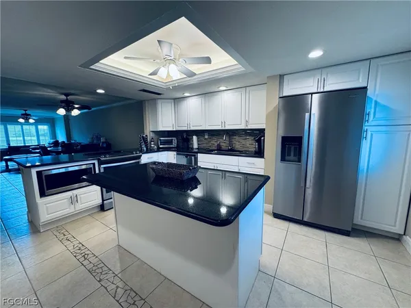 a kitchen with stainless steel appliances granite countertop a sink a microwave a refrigerator and white cabinets