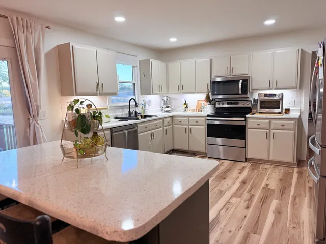 a kitchen with stainless steel appliances granite countertop a sink a stove a refrigerator a microwave oven with a dining table and chairs