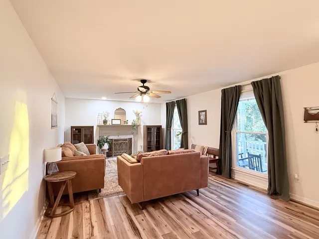 a living room with furniture large window and wooden floor