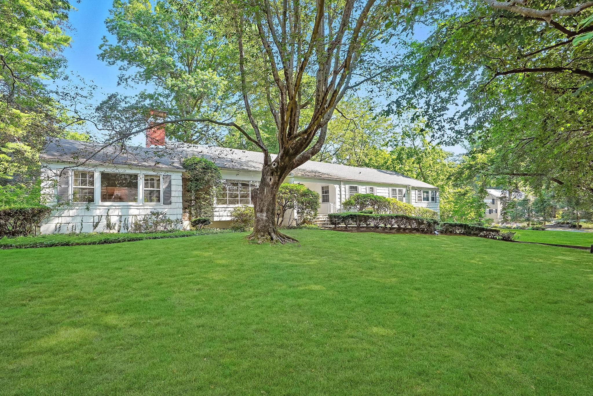 a view of a house next to a big yard and large trees