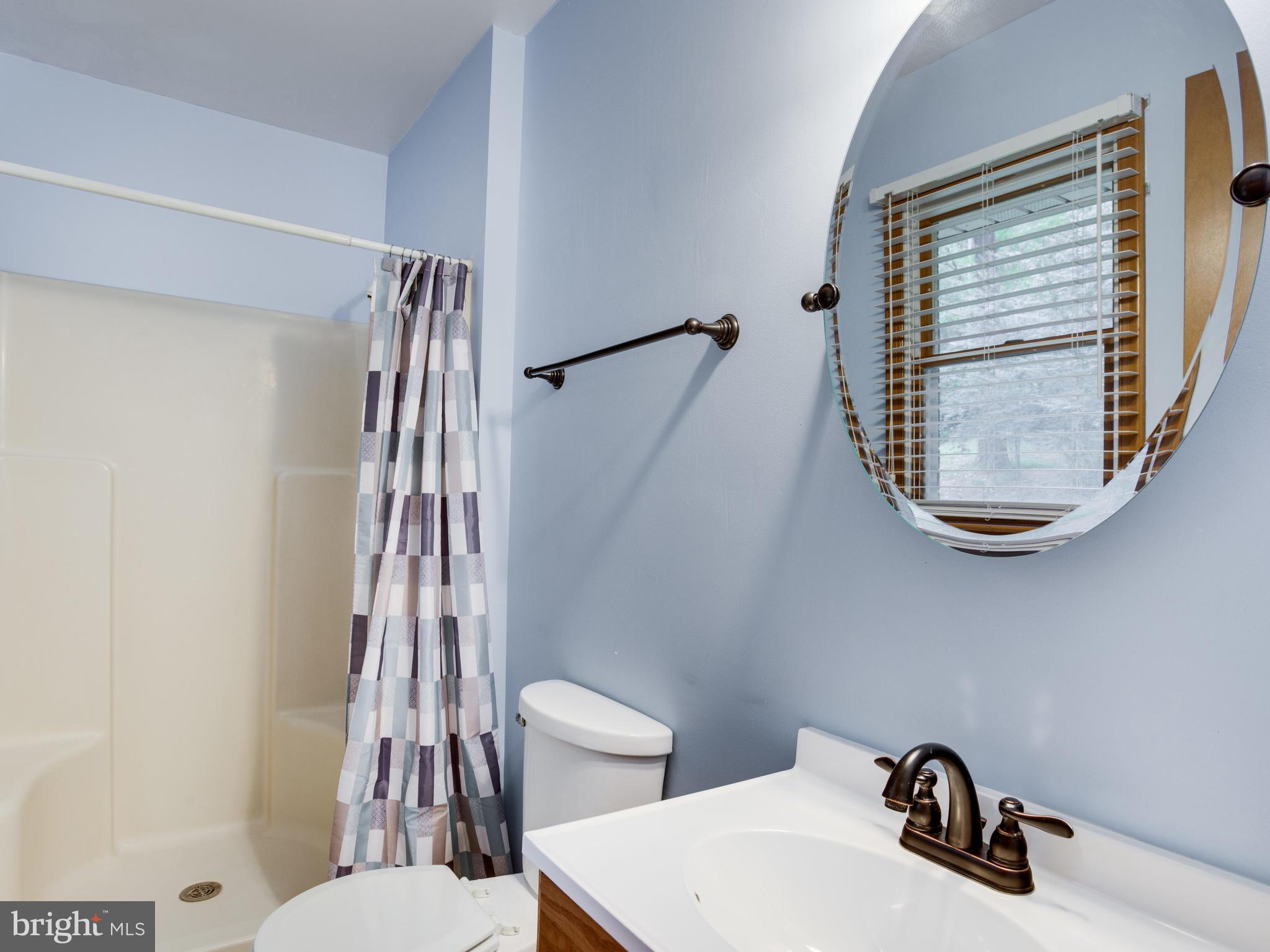11893 Little Cove Point Road Lusby, MD 20657 - Photo 17 of 18 a bathroom with a sink a mirror a toilet and a window