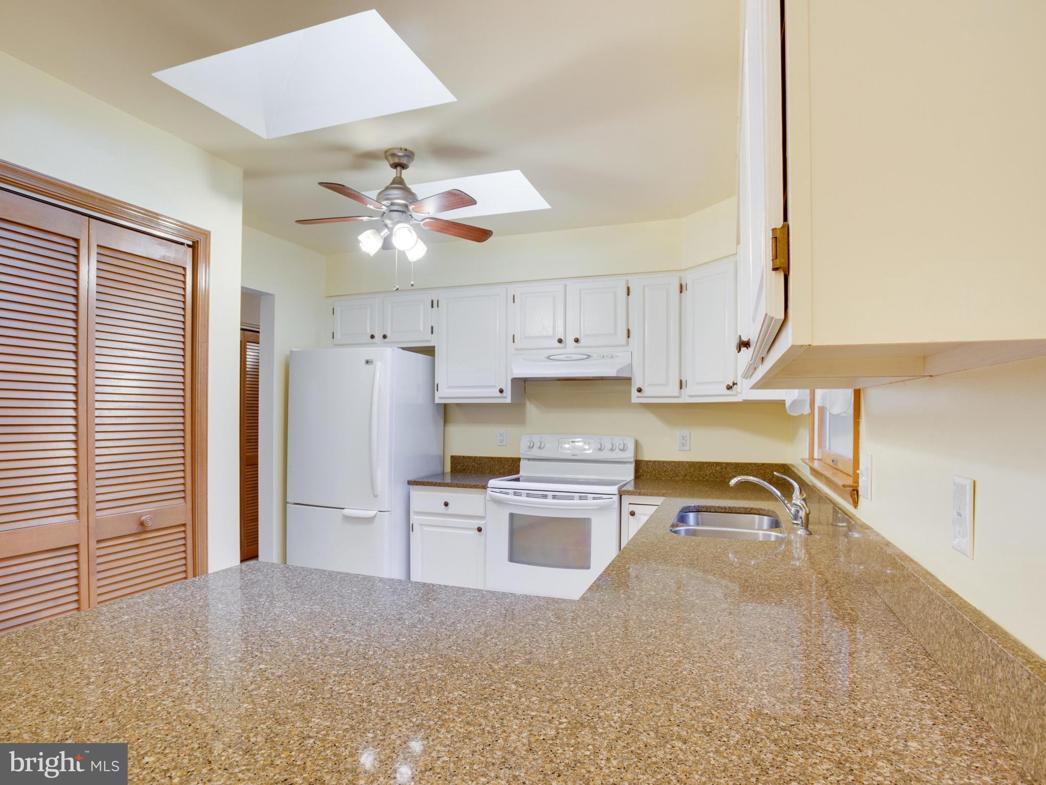11893 Little Cove Point Road Lusby, MD 20657 - Photo 6 of 18 a kitchen with a refrigerator a stove top oven a chimney cabinets and a dining table