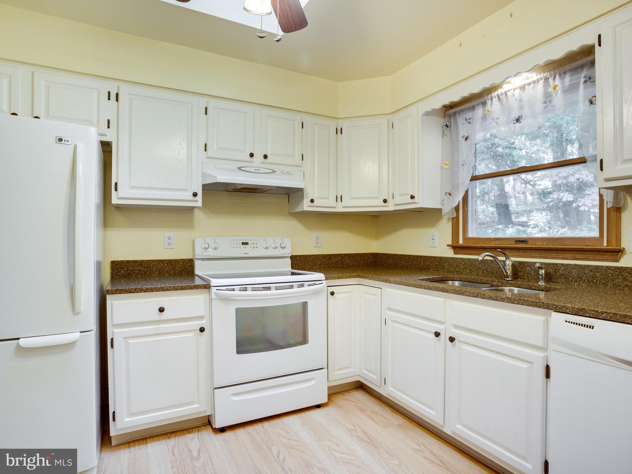 11893 Little Cove Point Road Lusby, MD 20657 - Photo 7 of 18 a kitchen with granite countertop white cabinets and white appliances