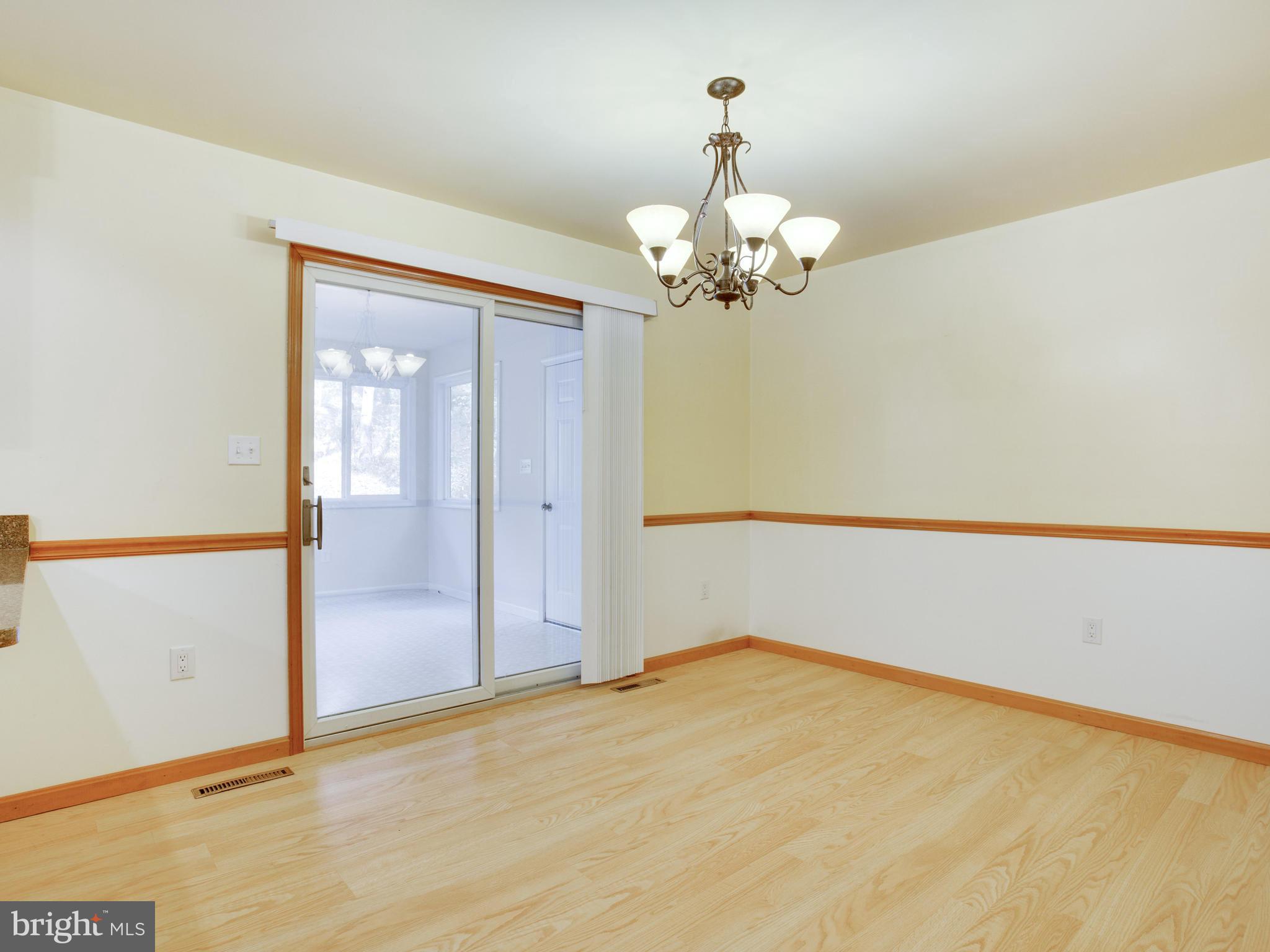 11893 Little Cove Point Road Lusby, MD 20657 - Photo 9 of 18 an empty room with chandelier fan and wooden floor