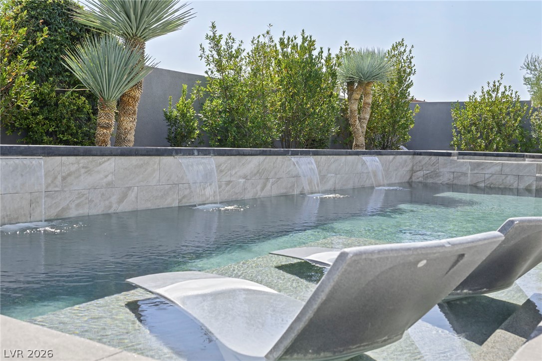 4208 Lapis Ridge Court Las Vegas, NV 89135 - Photo 45 of 61 Multiple water sheer descents spill into the pristine swimming pool lined with modern tiling.