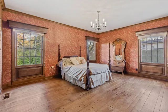 a spacious bedroom with a bed chandelier and window