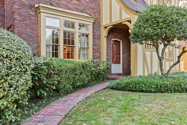a view of a brick house with a large windows and plants