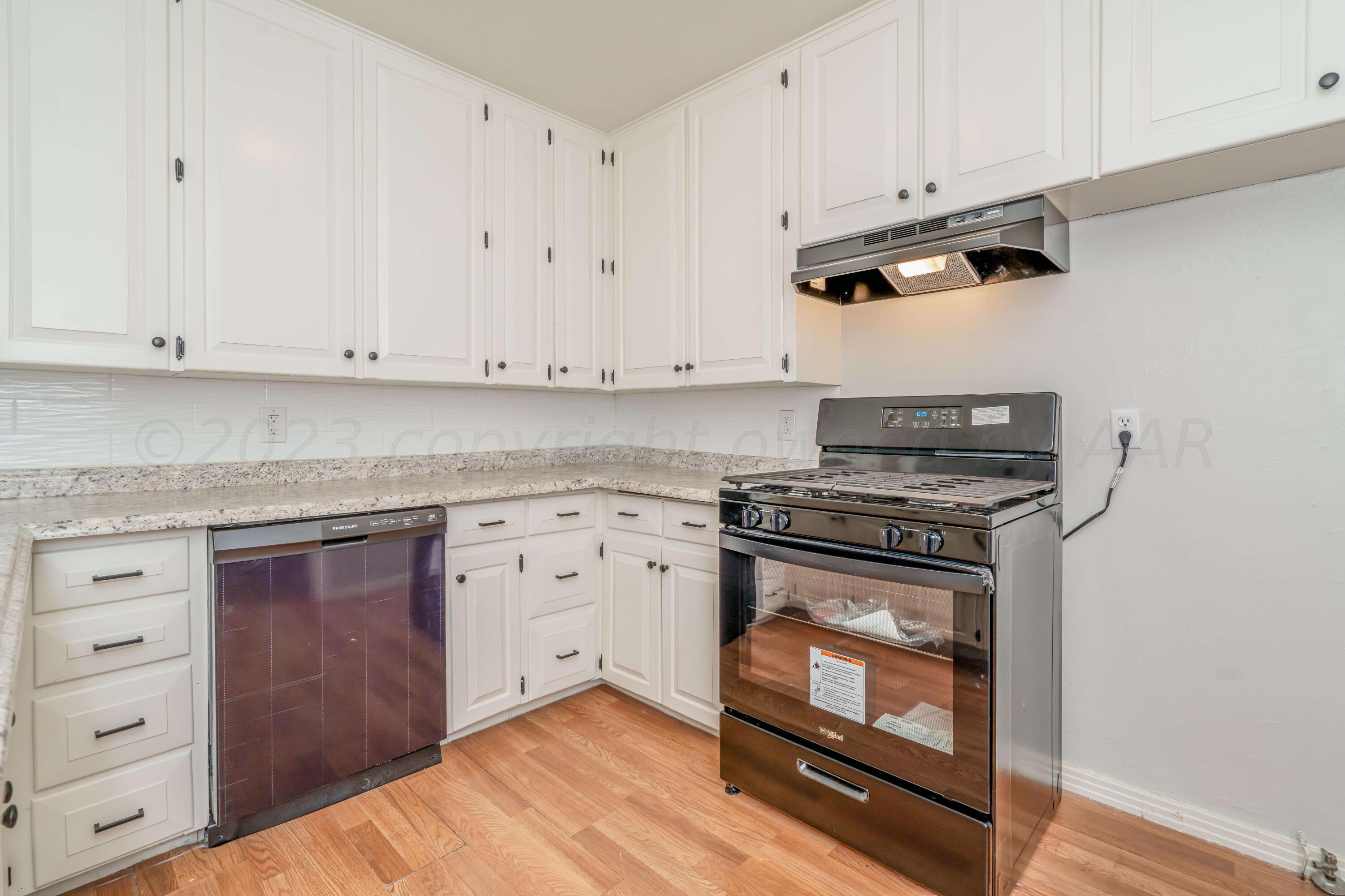 4306 Parker Street Amarillo, TX 79110 - Photo 11 of 29 a kitchen with granite countertop cabinets stainless steel appliances and wooden floor