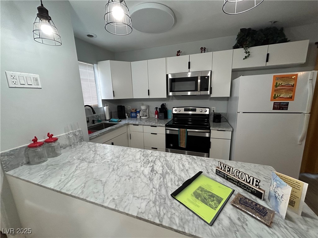 5045 Spencer Street, Unit B Las Vegas, NV 89119 - Photo 5 of 23 Kitchen featuring stainless steel appliances, white cabinets, and decorative light fixtures