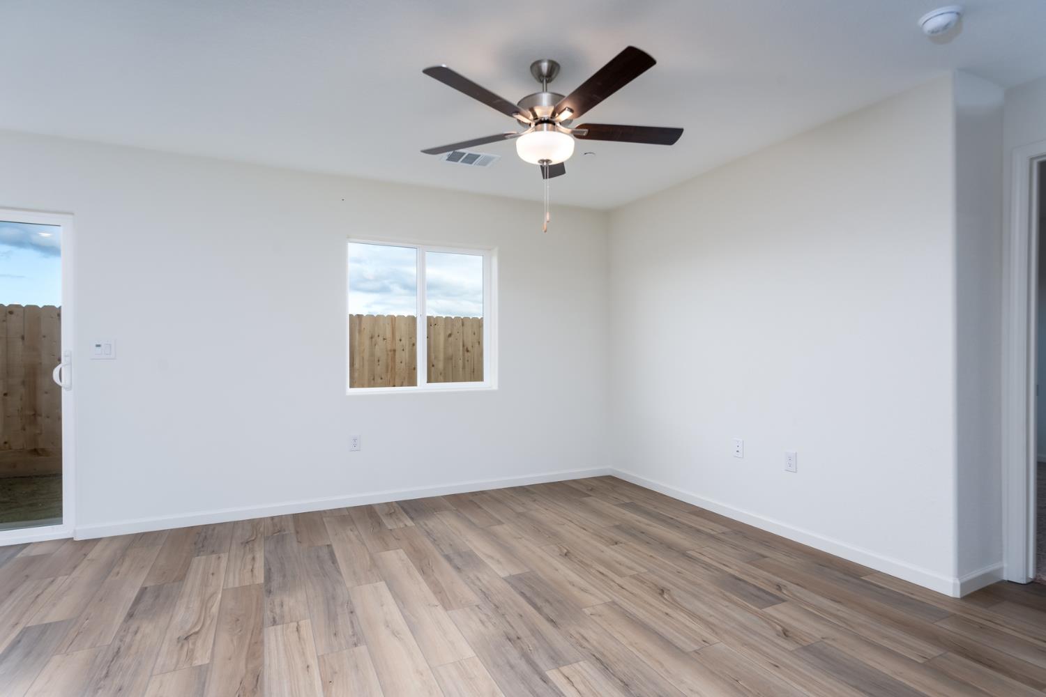 2265 Travis Court Newman, CA 95360 - Photo 6 of 12 an empty room with wooden floor and ceiling fan