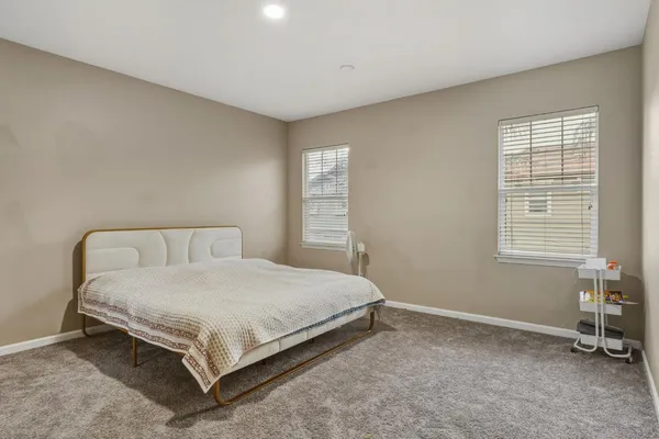 a bedroom with a bed a table and windows