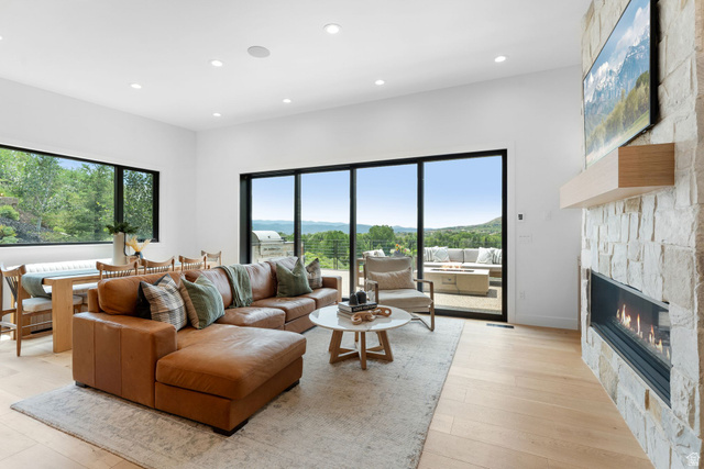 1400 Weber Wild Road Oakley, UT 84055 - Photo 16 of 55 Spacious living area featuring a stone-clad fireplace with a built-in mantel, expansive sliding glass doors, large picture windows, recessed lighting, and light wood-finish flooring