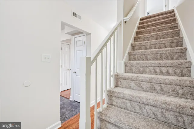 a view of staircase with white walls and white door