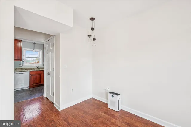 a view of a hallway with wooden floor and a bathroom