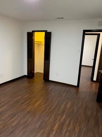 a view of empty room with wooden floor and window