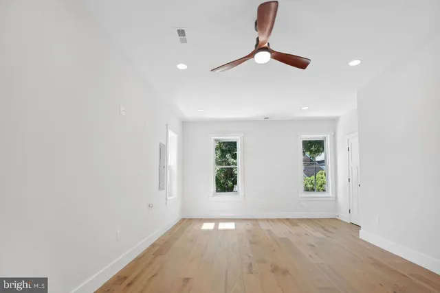 an empty room with windows and ceiling fan