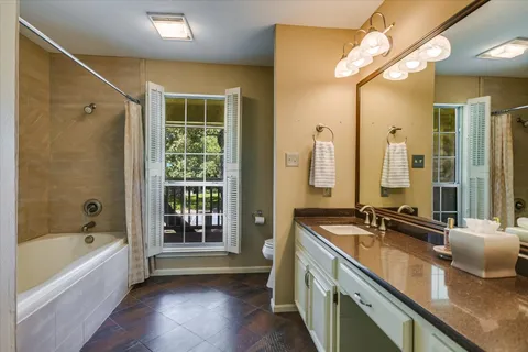 a bathroom with a granite countertop tub sink a mirror and a bathtub