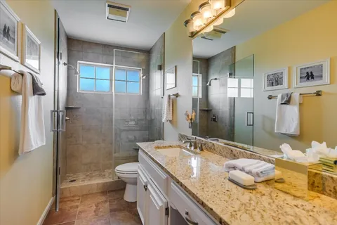 a bathroom with a granite countertop sink a toilet and shower