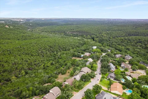 an aerial view of residential house with outdoor space and trees all around