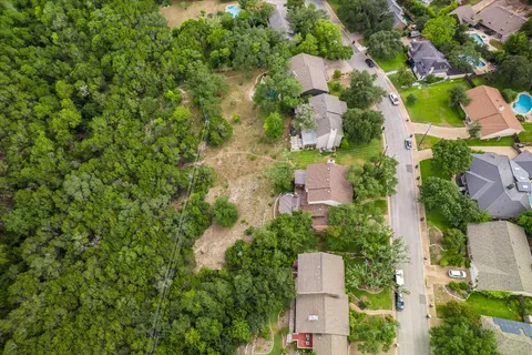 an aerial view of residential houses with outdoor space and trees