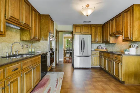 a kitchen with stainless steel appliances granite countertop a refrigerator a stove top oven sink and cabinets with wooden floor