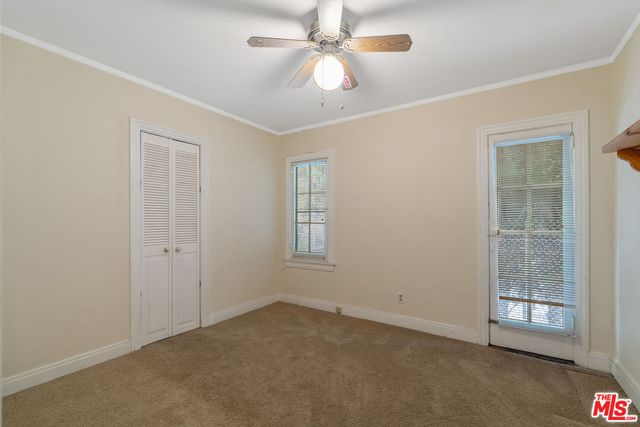 an empty room with windows and fan