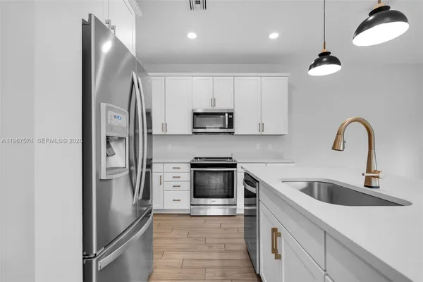 a kitchen with stainless steel appliances granite countertop a refrigerator a sink a stove and a microwave