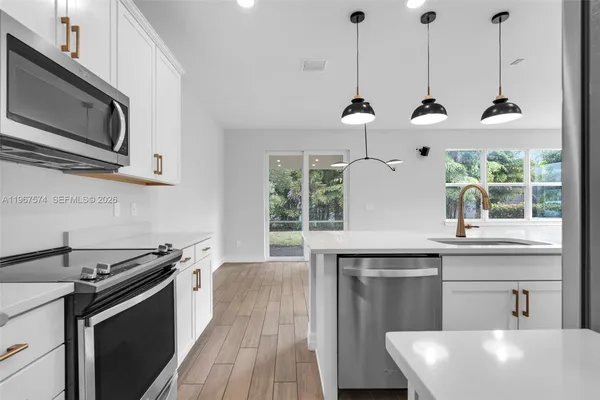 a kitchen with stainless steel appliances a sink a stove a microwave and wooden floor