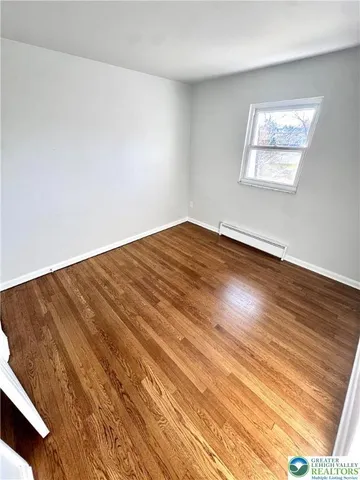 an empty room with wooden floor and entrance