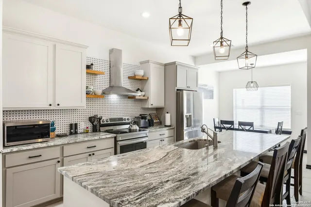 a kitchen with stainless steel appliances granite countertop a stove a sink a refrigerator and wooden cabinets