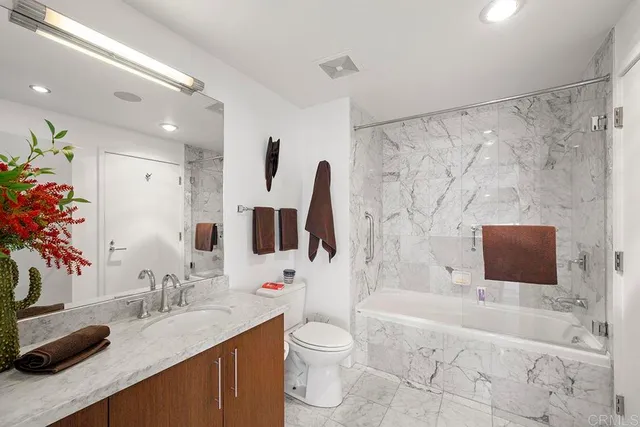 a bathroom with a granite countertop sink toilet mirror and bathtub