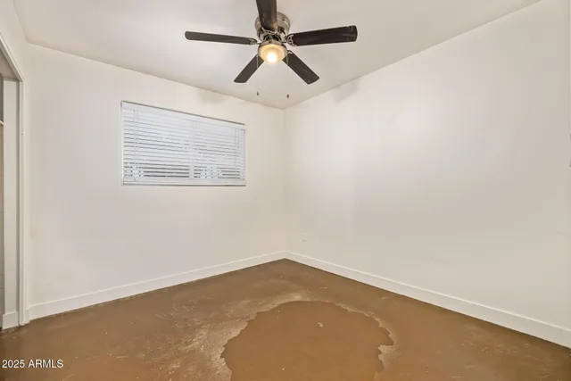 an empty room with a ceiling fan and carpet