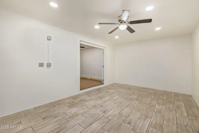 a view of a room with a ceiling fan and hardwood floor