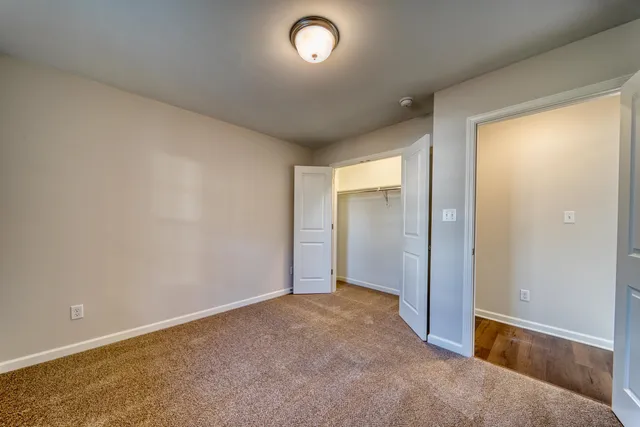 an empty room with closet area and windows