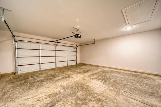 a view of an empty room with wooden floor and a kitchen