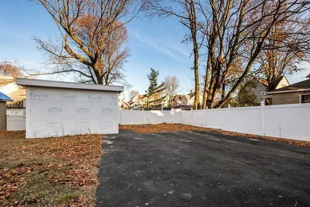 a view of a white house with large trees next to a road
