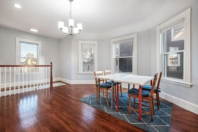 a dining room with wooden floor a chandelier a wooden table and chairs