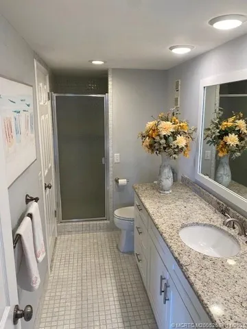 a bathroom with a granite countertop sink a toilet and shower